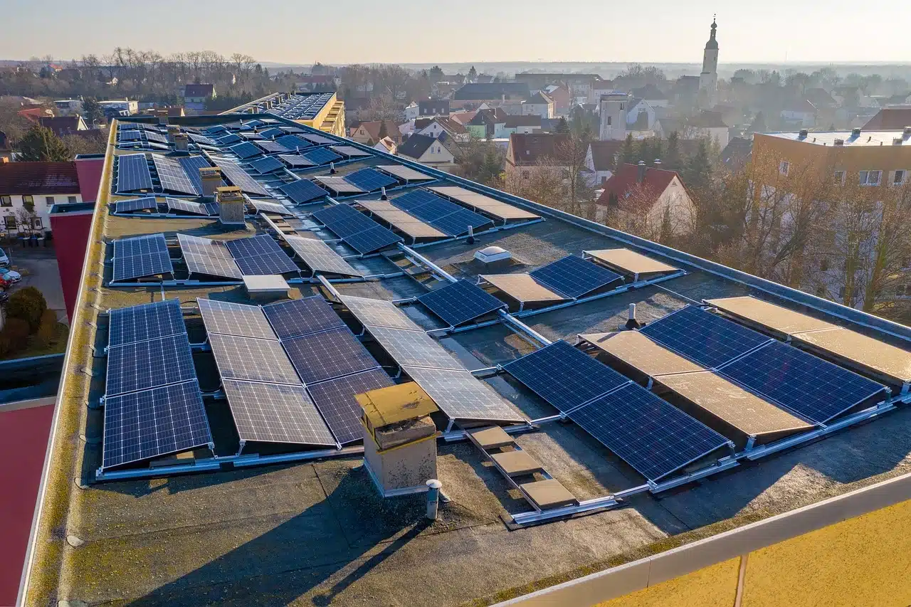 Eine Solaranlage auf einem Flachdach mit einer Stadt im Hintergrund.