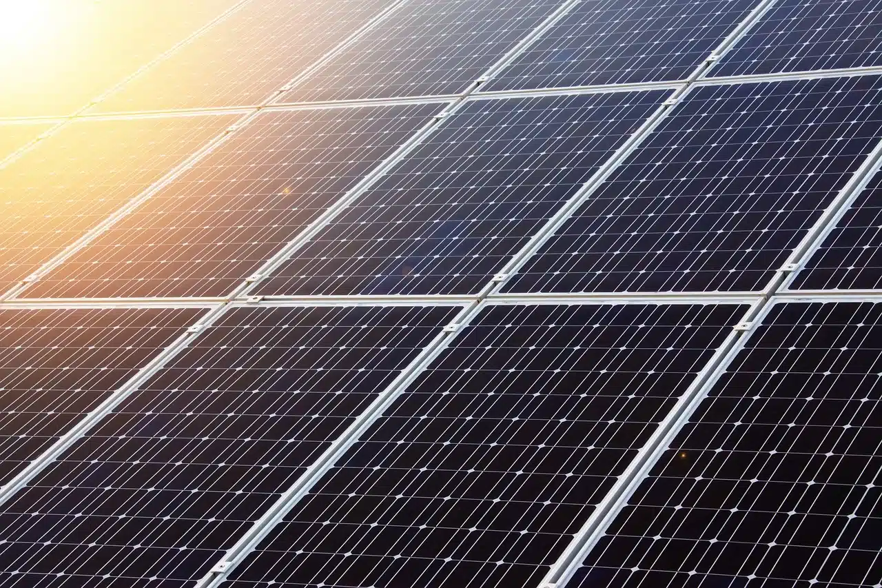 Eine Nahaufnahme eines Solarpaneels mit Sonnenschein am linken Rand des Bildes.