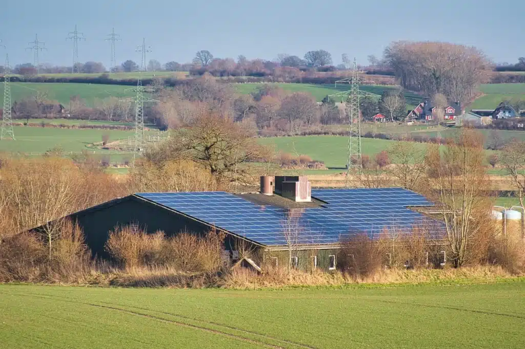Ein Bauernhaus mit Solardach, umgeben von Feldern und Bäumen.