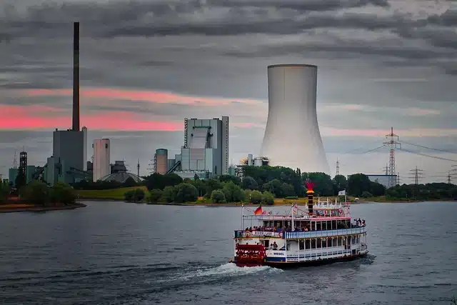 Ein Schiff auf einem Fluss vor einem Kraftwerk.