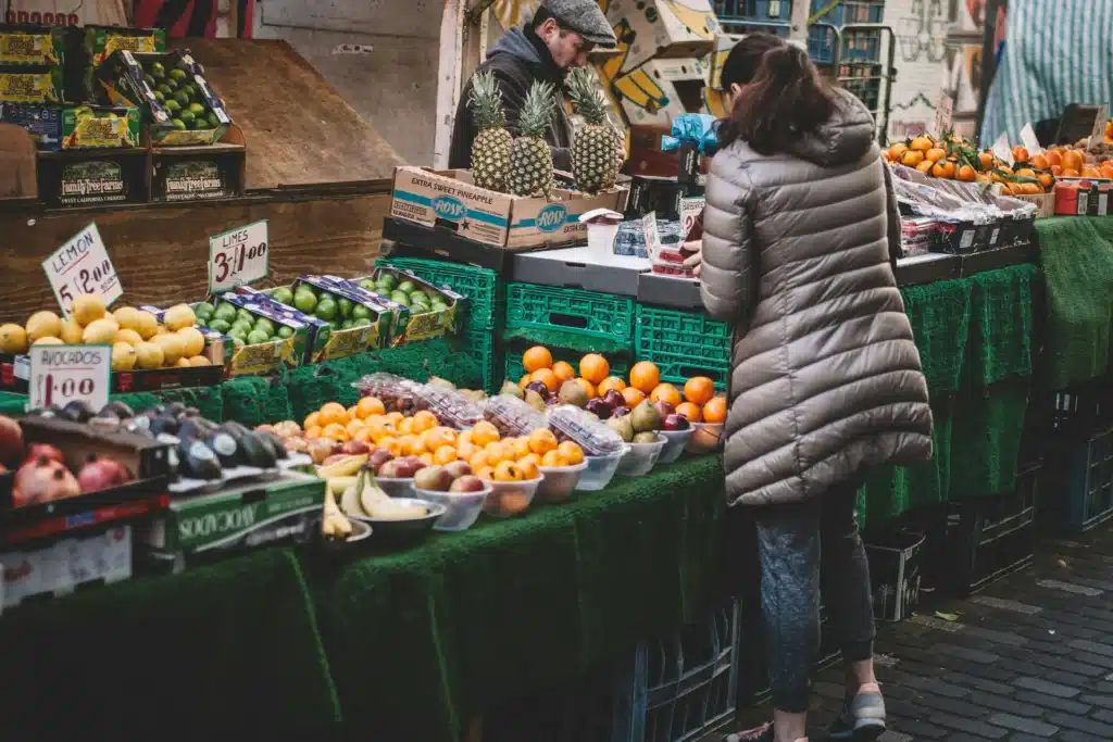 Eine Frau steht an einem Marktstand vor Gemüse und Obst. (Foto: Clem Onojeghuo/Pexels)