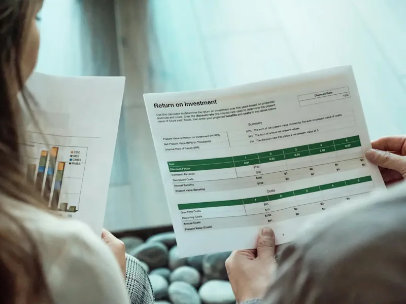 Zwei Personen vergleichen Investment-Entwicklungen auf Papier. (Foto: Kindel Media/Pexels)