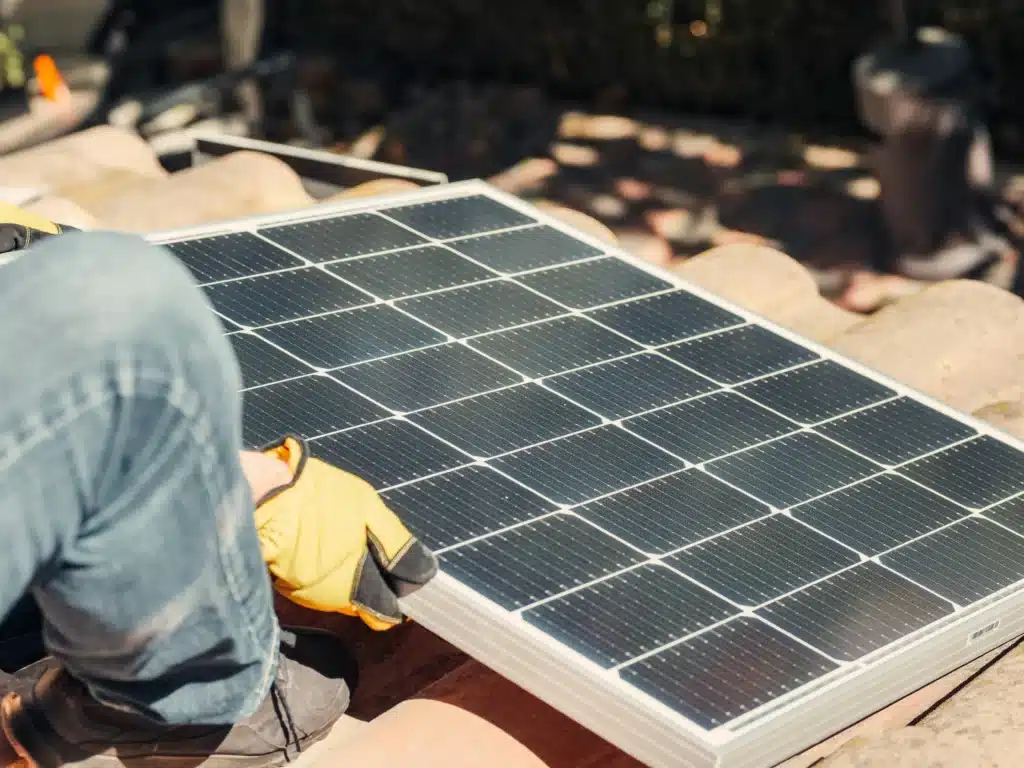 Ein Mann installiert ein Solarmodul auf einem Dach. (Foto: Pexels)