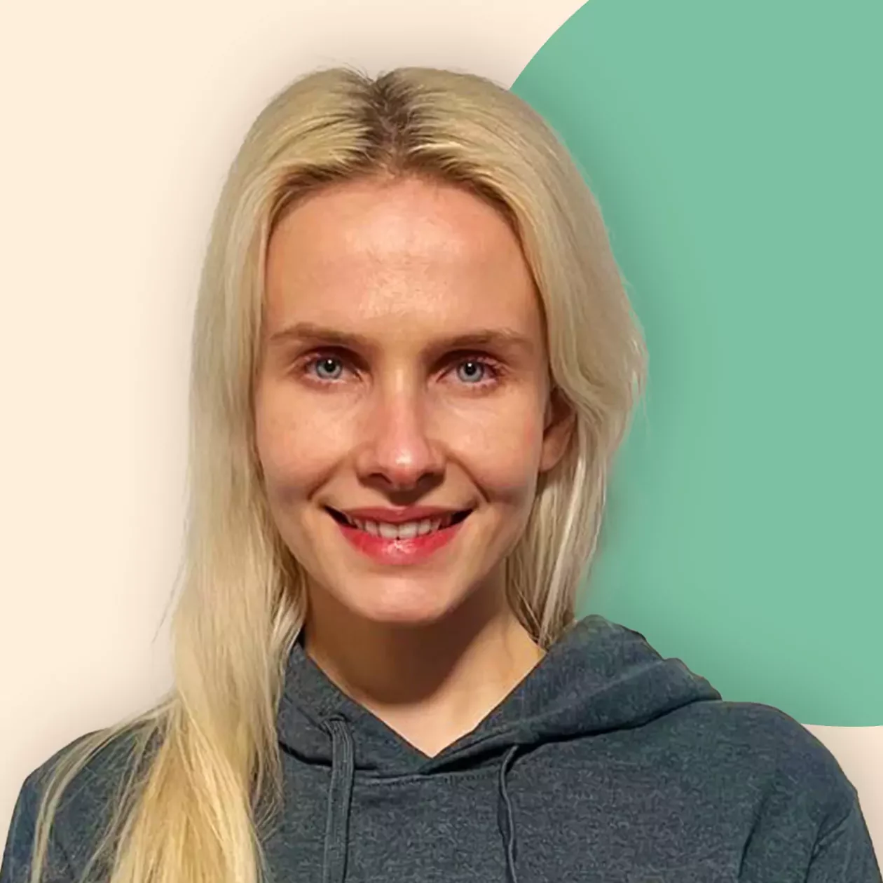 Eine Frau mit langen blonden Haaren lächelt in die Kamera. Sie trägt einen grauen Kapuzenpullover mit dem Aufdruck PEEAktuell, der ihr Interesse an Erneuerbaren Energien widerspiegelt. Der Hintergrund ist hell mit einem grünen, runden Akzent.
