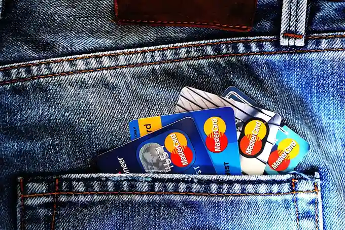 Mehrere Kredit- und Debitkarten, darunter MasterCard, ragen teilweise sichtbar aus der Vordertasche der Blue Denim-Jeans heraus, ähnlich wie beim Vergleich des täglichen Zugriffs auf Tagesgeld- und Festgeldkonten.