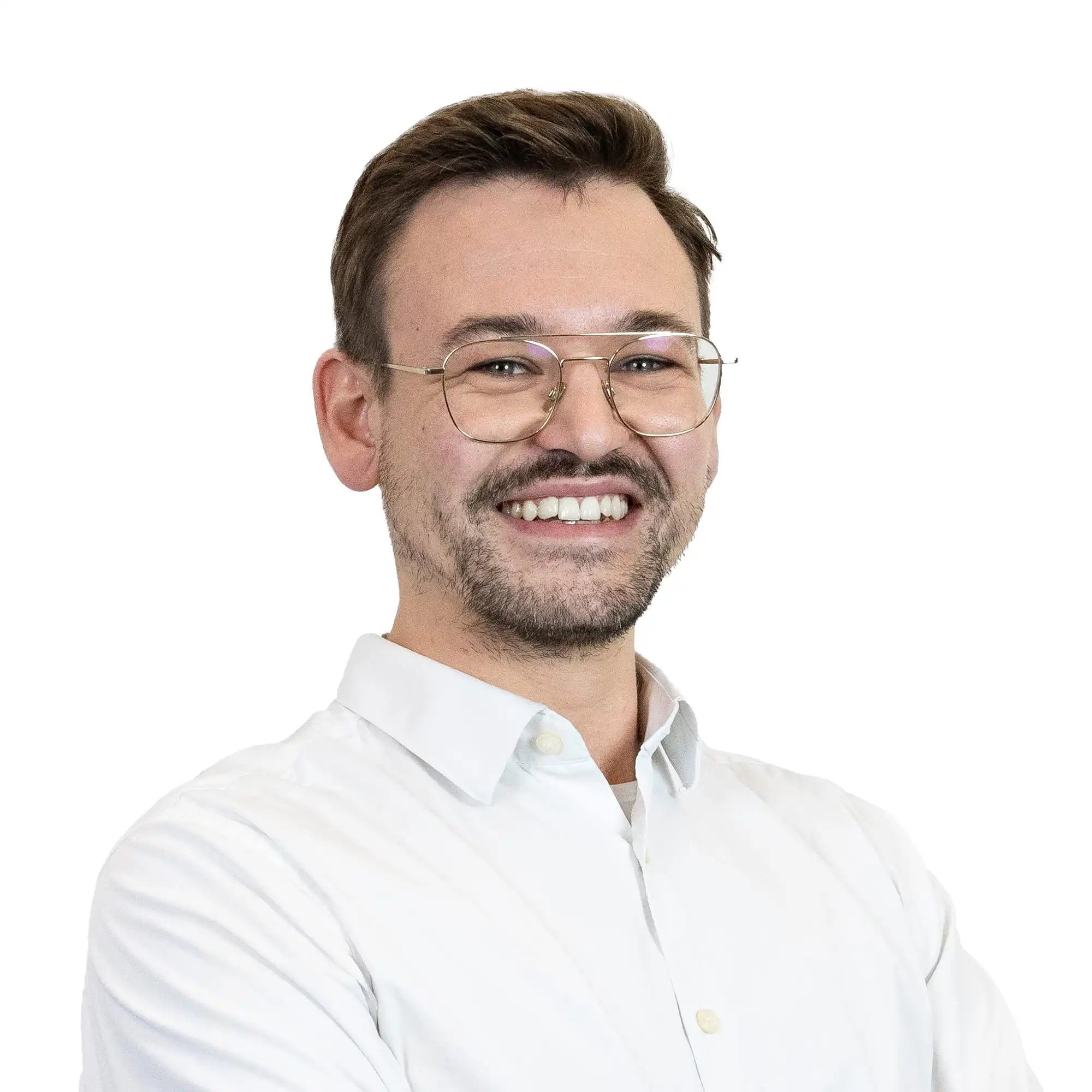 Ein lächelnder Mann mit kurzen braunen Haaren, Brille und gestutztem Bart trägt ein weißes Button-up-Hemd. Er steht mit verschränkten Armen vor einem schlichten weißen Hintergrund.