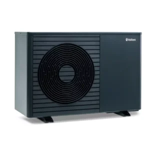 Ein modernes, rechteckiges, schwarzes Wärmepumpengerät mit einem kreisförmigen Entlüftungsmuster auf der linken Seite und dem Vaillant-Logo oben rechts, das auf zwei kleinen schwarzen Füßen vor einem weißen Hintergrund steht.