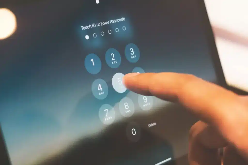 Eine Hand gibt auf einem Touchscreen-Gerät mit beleuchteten Zifferntasten und unscharfem Hintergrund einen Passcode ein – als Teil eines Sicherheitschecks mit Zwei-Faktor-Authentifizierung.