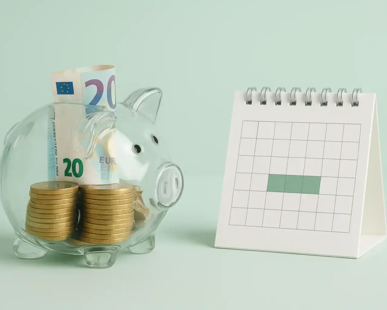 Ein transparentes Sparschwein, gefüllt mit Euro-Münzen und -Banknoten, steht neben einem kleinen Spiral-Kalender mit einer grün hervorgehobenen Woche, der die Sparplanung und den Vergleich zwischen Tagesgeld und Festgeld vor einem pastellgrünen Hintergrund symbolisiert.