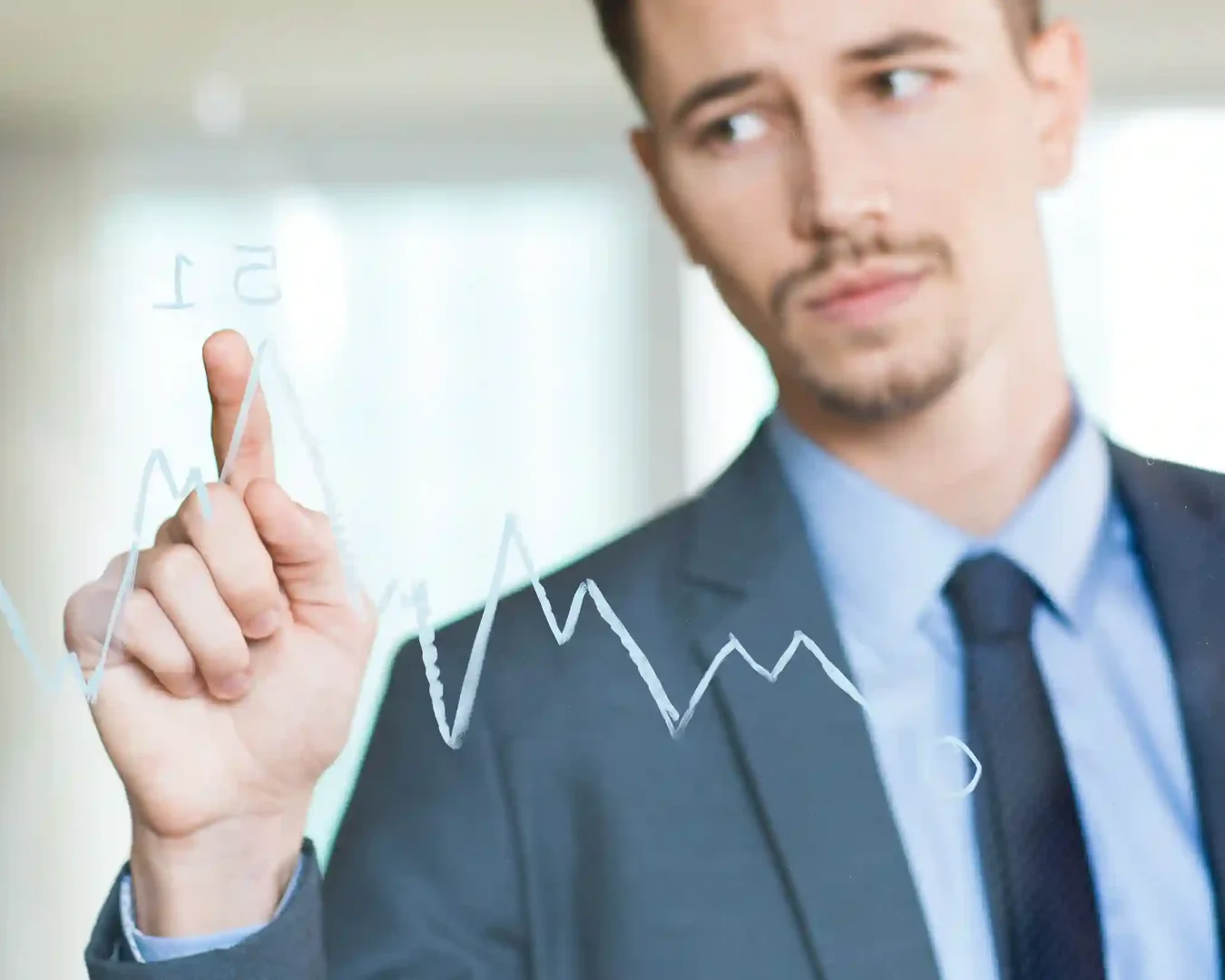 Ein Mann im Anzug berührt einen transparenten Bildschirm, auf dem ein fluktuierendes Liniendiagramm angezeigt wird, und wirkt konzentriert, während er die Daten analysiert - ähnlich wie bei den Bewertungen, die man bei Traders Place Erfahrungsungen findet.