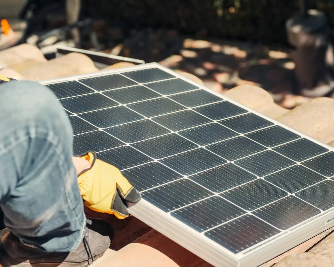 Ein Mann installiert ein Solarmodul auf einem Dach. (Foto: Pexels)