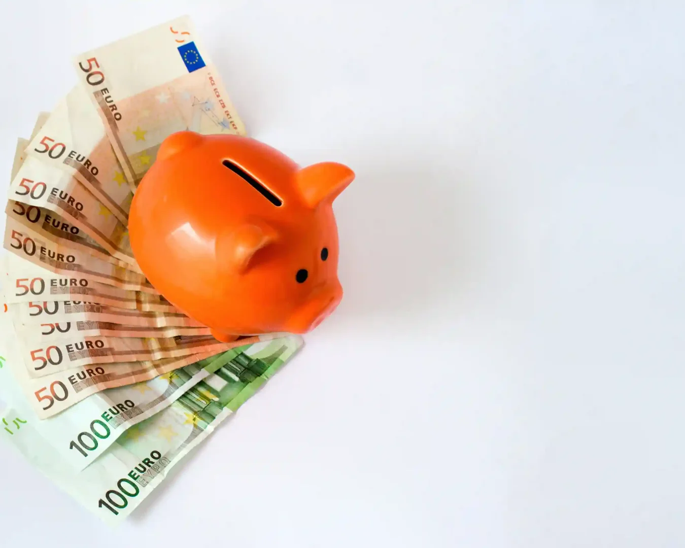 Ein orangefarbenes Sparschwein steht auf einer weißen Fläche, umgeben von aufgefächerten 50- und 100-Euro-Scheinen - ein cleveres Bild für alle, die eine Tagesgeld-Alternative suchen.