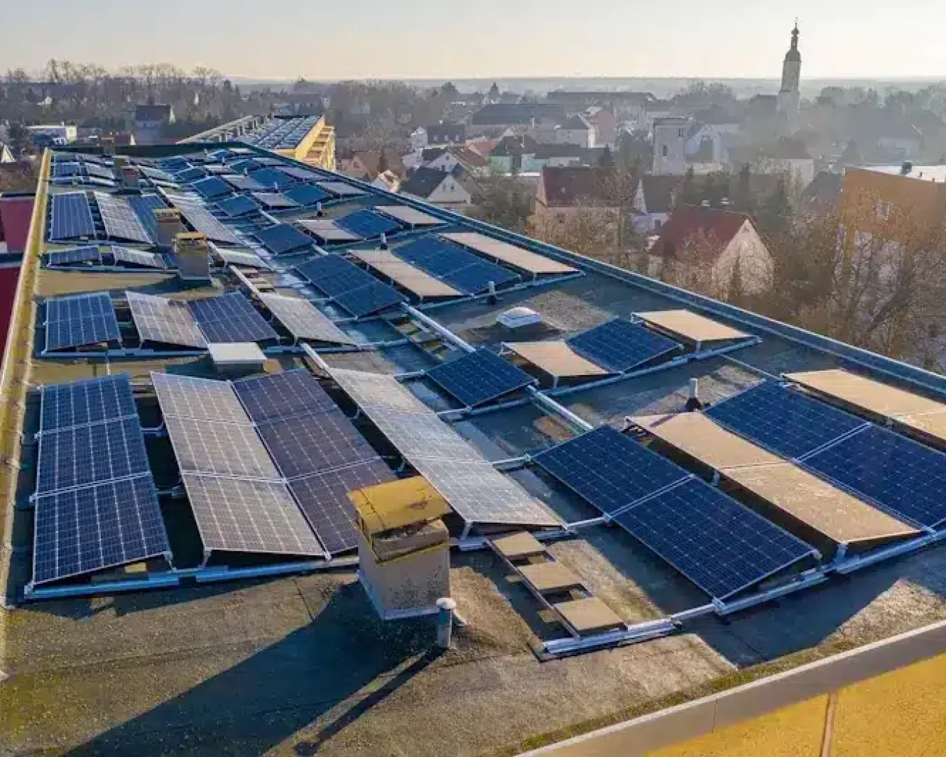 Eine Solaranlage auf einem Flachdach mit einer Stadt im Hintergrund.